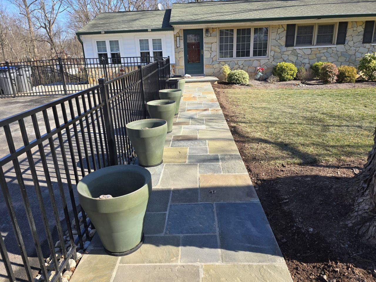 A stone walkway leading to a house with potted plants on it
