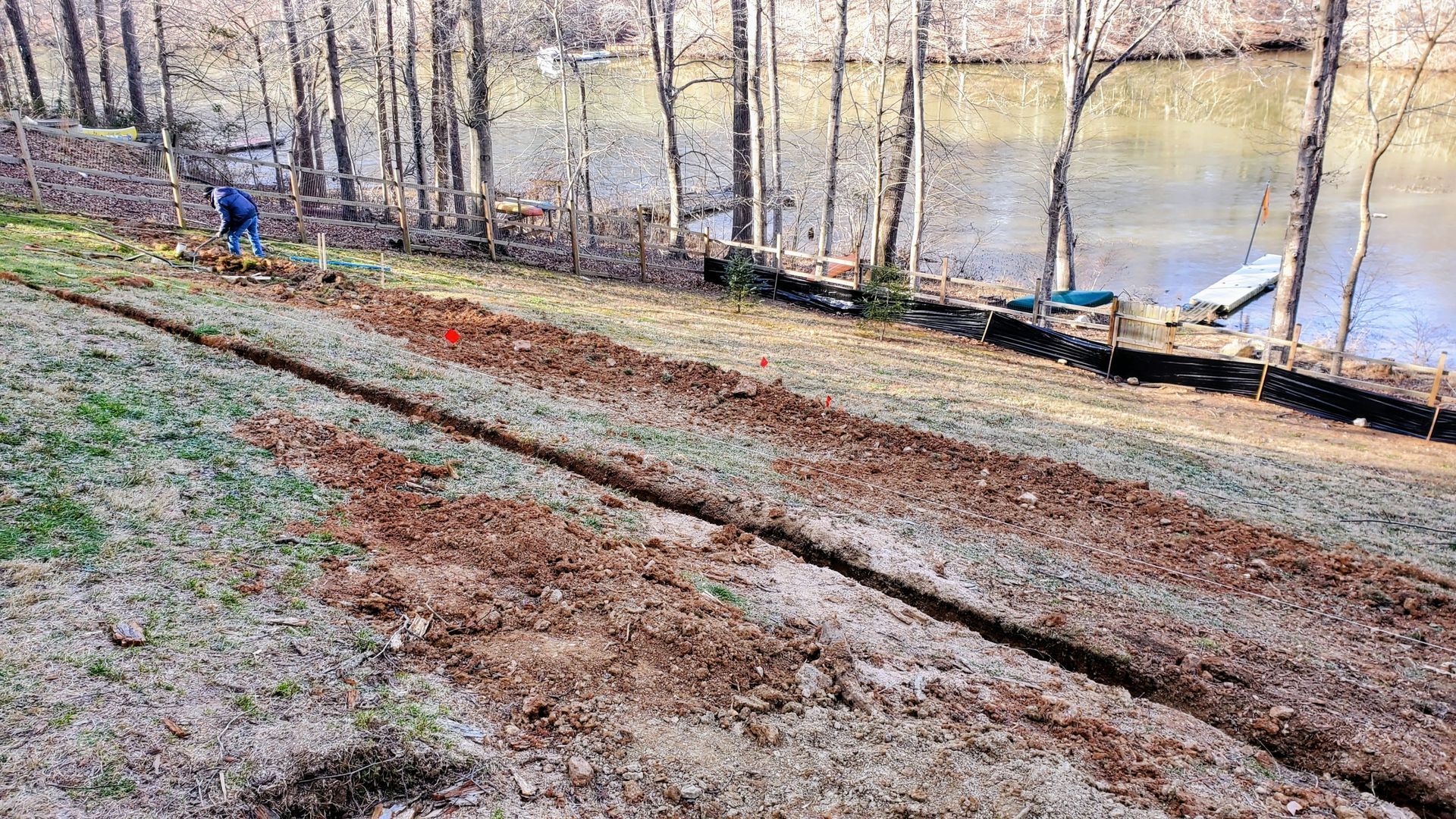 A person is digging a hole in the ground next to a body of water.
