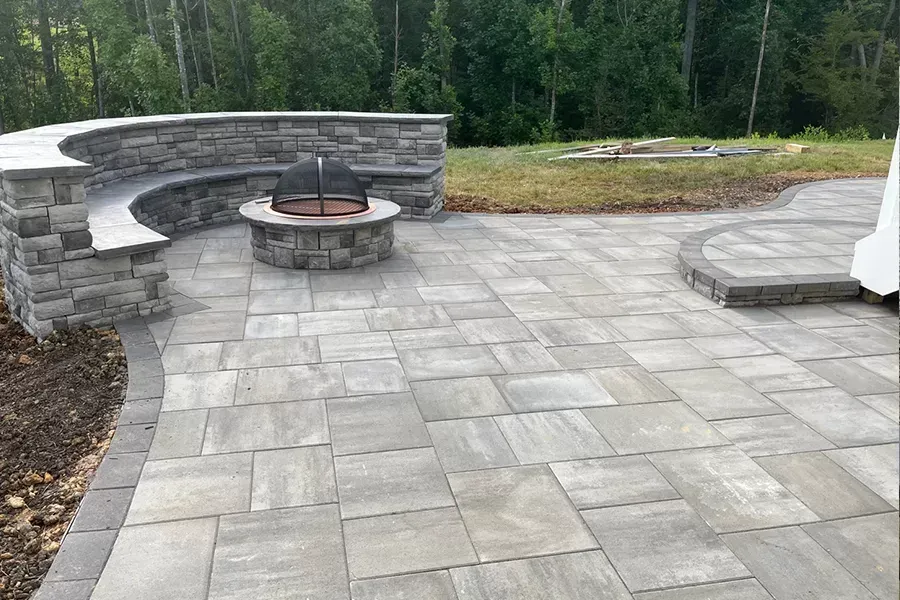 A patio with a fire pit and a stone wall.