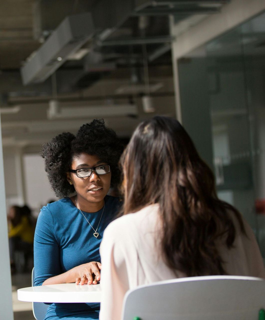 Two women are sitting at a table having a conversation.