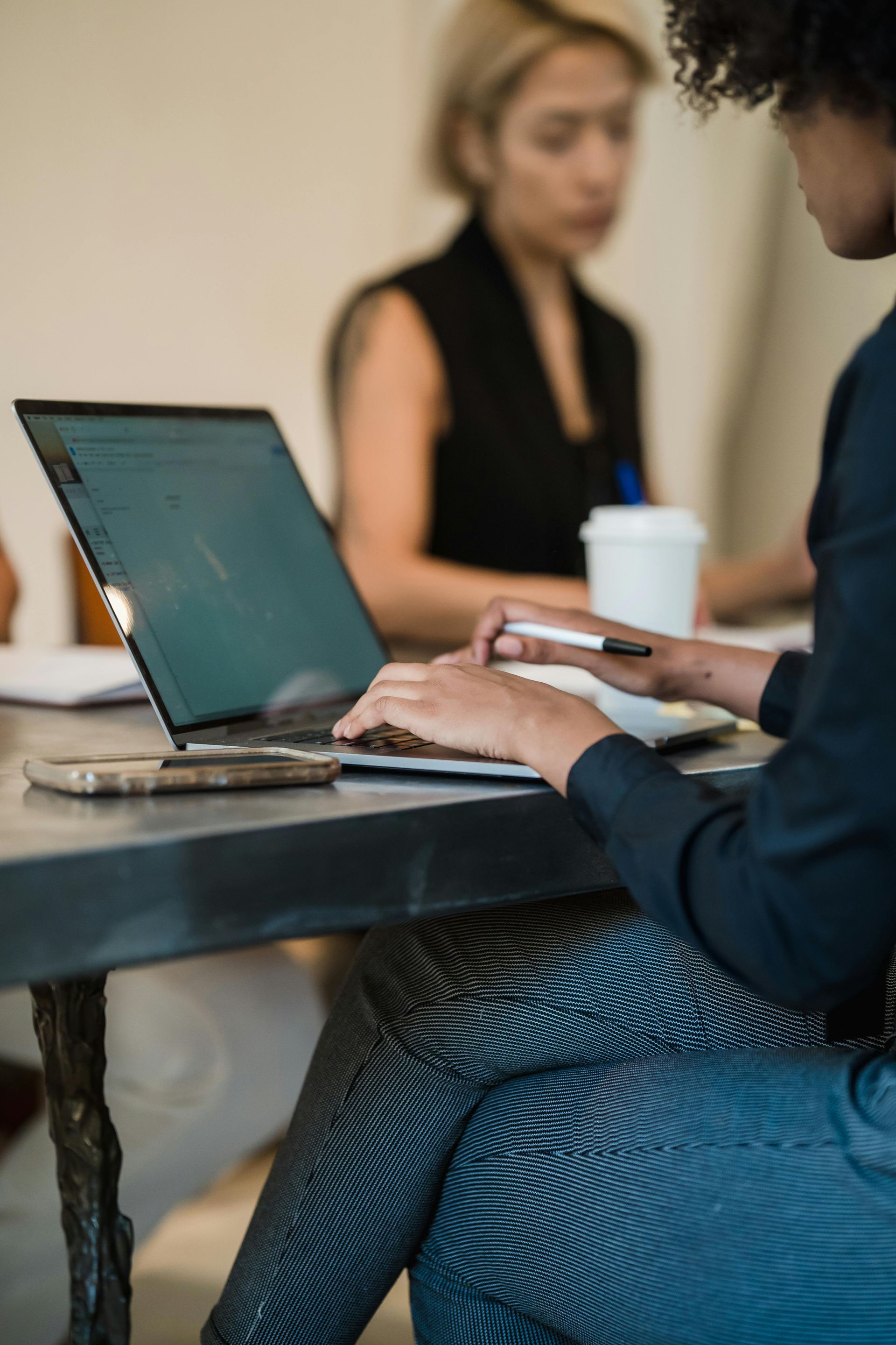A woman is sitting at a table using a laptop computer.
