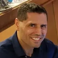 A man in a blue shirt is smiling for the camera.