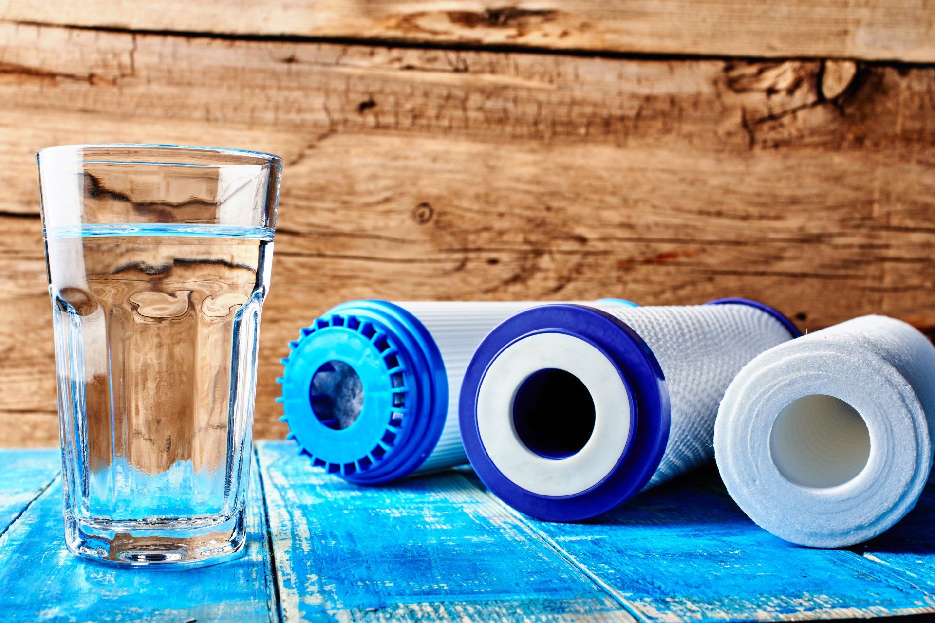 Water filters. Carbon cartridges and a glass of water on a wooden background.