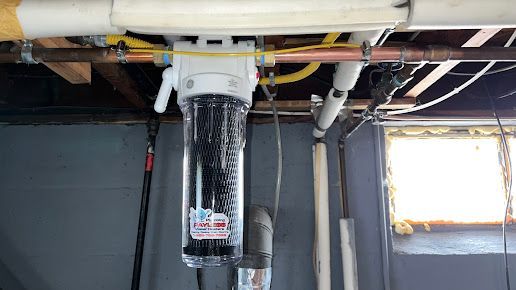 A water filter is hanging from the ceiling in a basement.