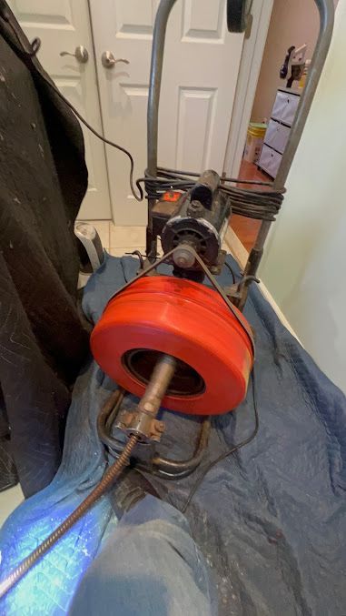 A drain cleaner is sitting on top of a blue cloth on the floor.