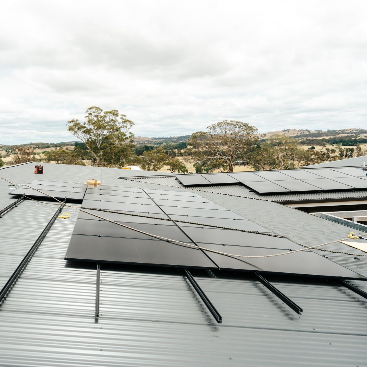 Solar panels installed on a metal roof, with a landscape view in the background.