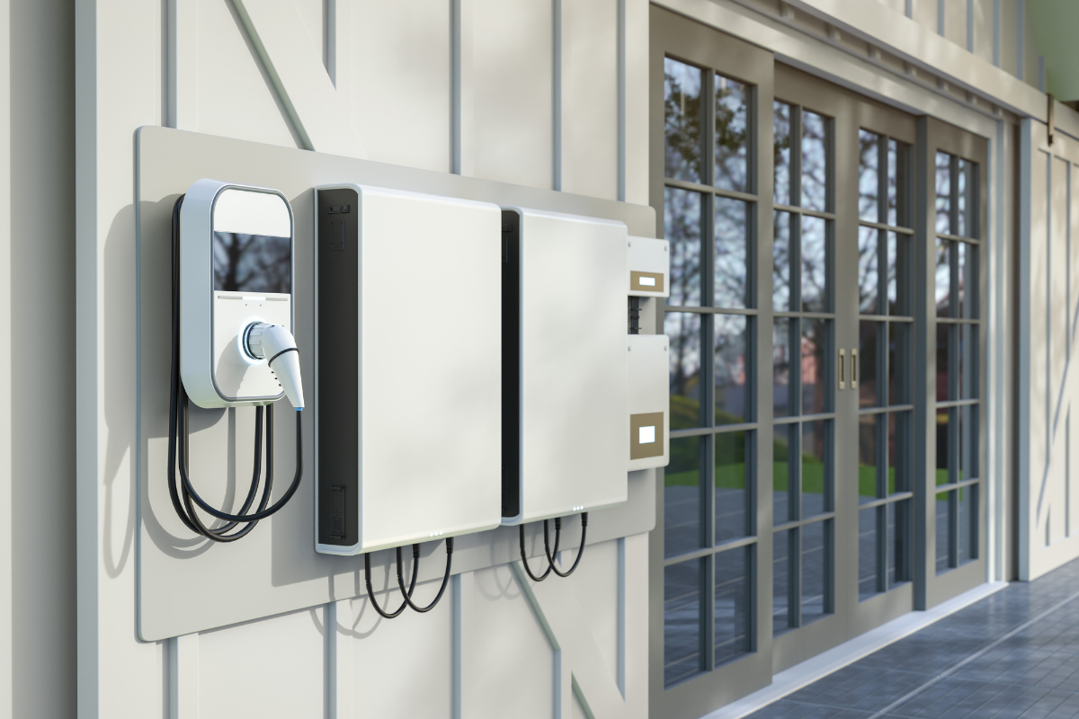 EV charger and battery system mounted on a white wall, near glass doors.