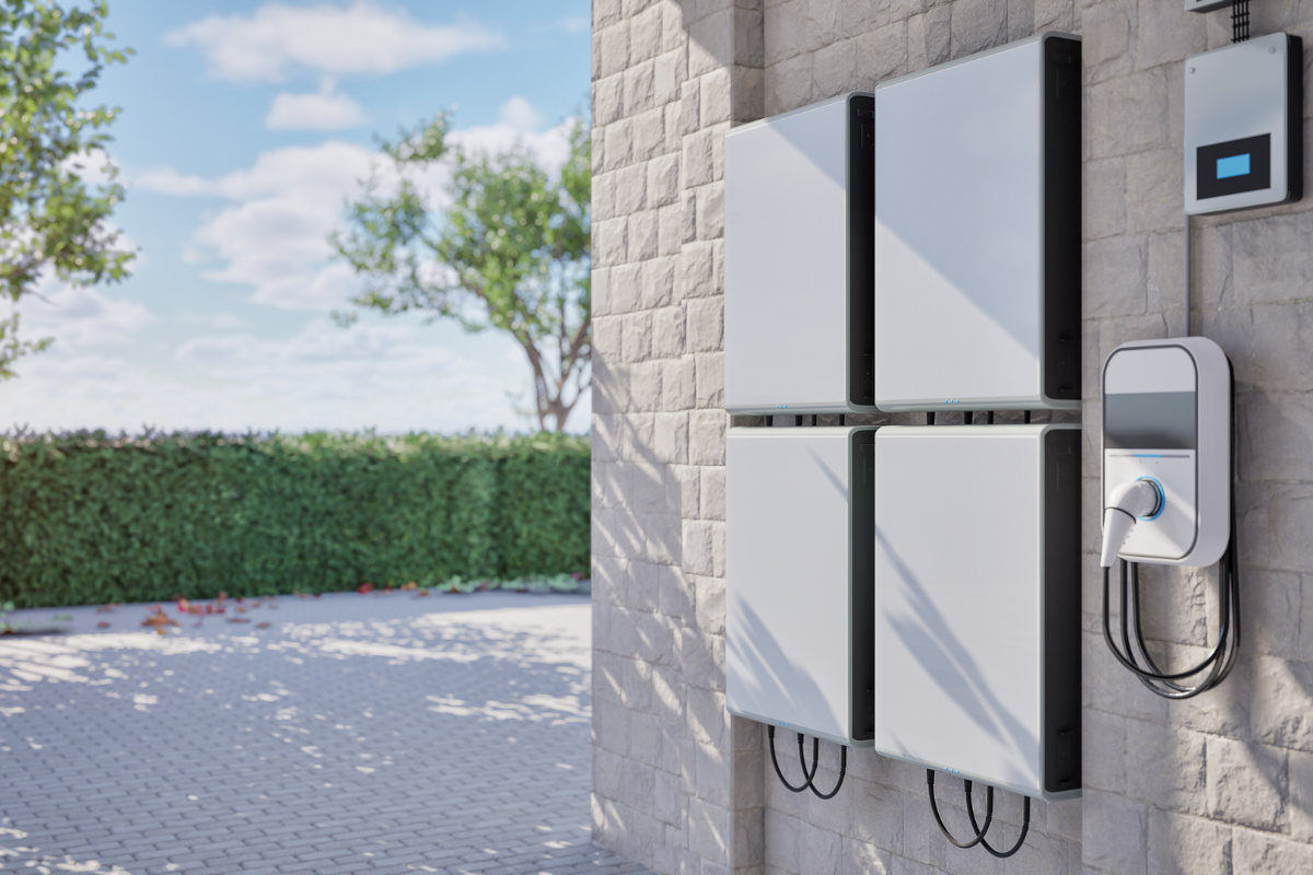 White solar battery storage units mounted on a brick wall next to an EV charger.