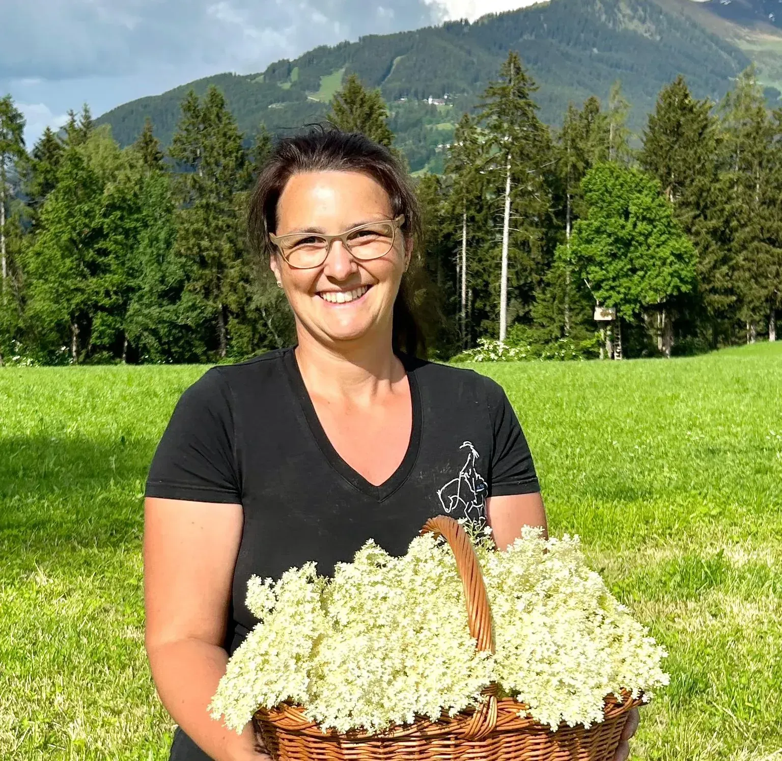 Eine Frau hält einen Korb mit Blumen auf einem Feld