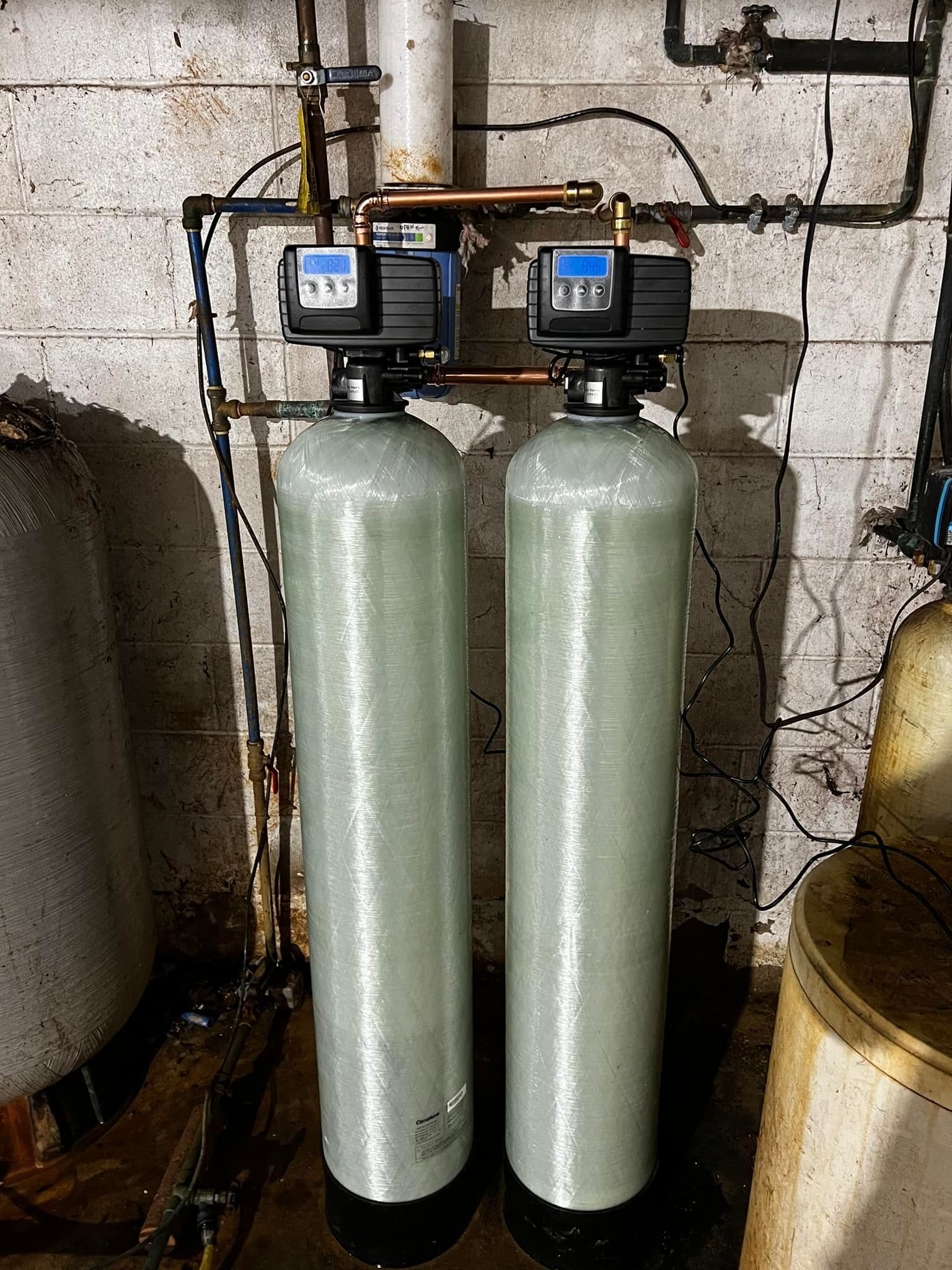 Two white air conditioning units mounted on an aged, weathered building exterior.