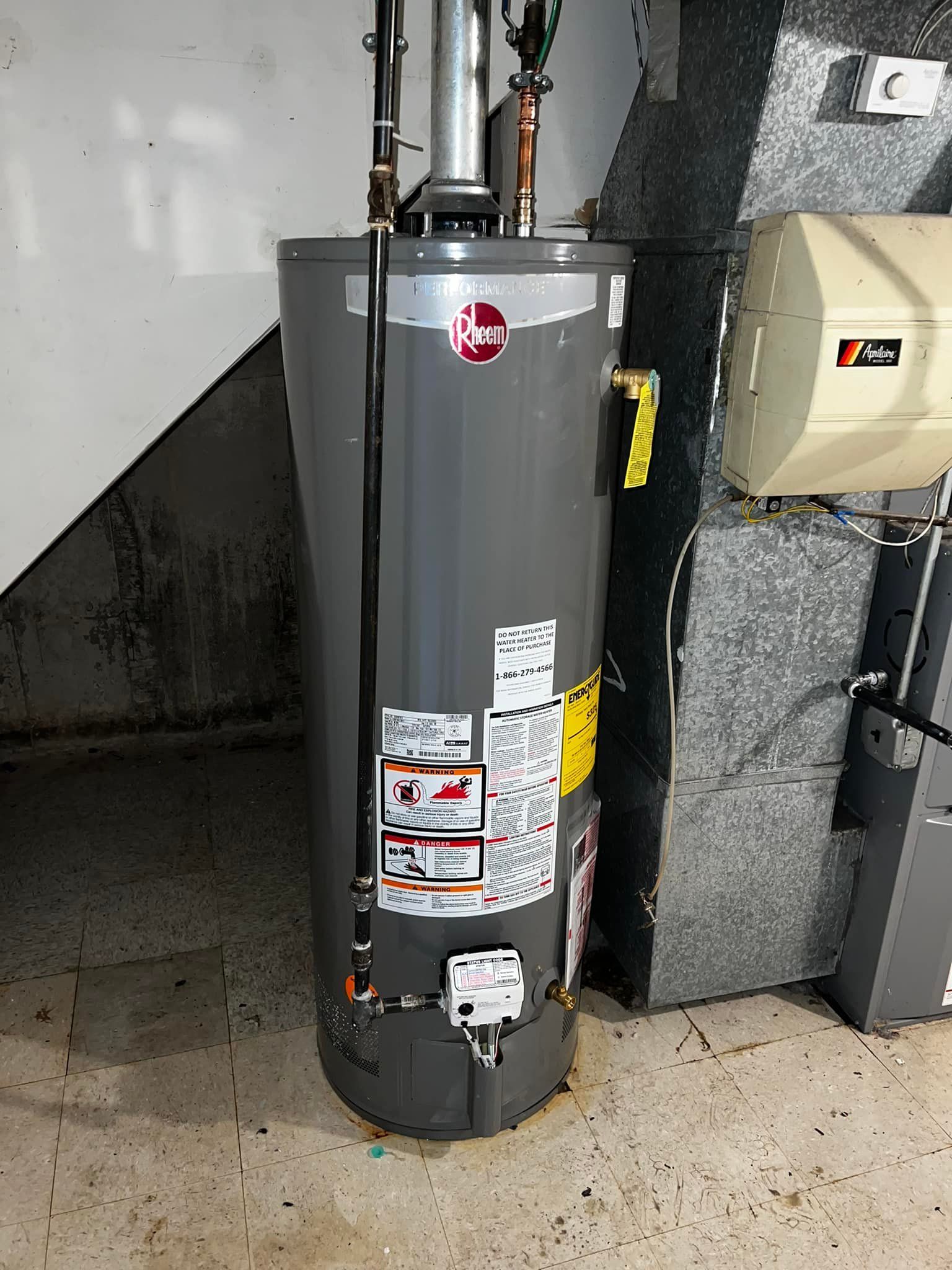Gray water heater in a basement setting with ductwork and a humidifier.