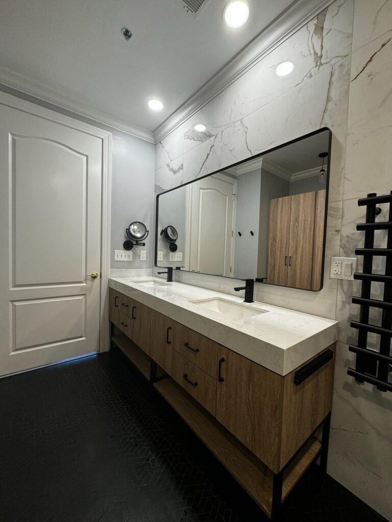 Modern bathroom with a double vanity, large mirror, and black accents.