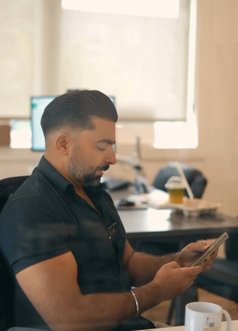 A man is sitting at a desk looking at his phone