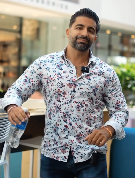 A man in a floral shirt is holding a bottle of water