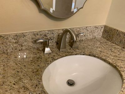 A bathroom sink with a granite counter top and a mirror.
