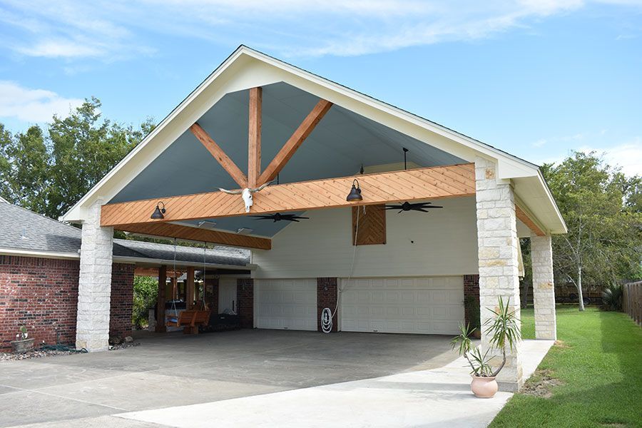 A large white garage with a wooden roof and a ceiling fan.
