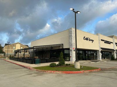 A large white building with a lot of windows and a parking lot in front of it.