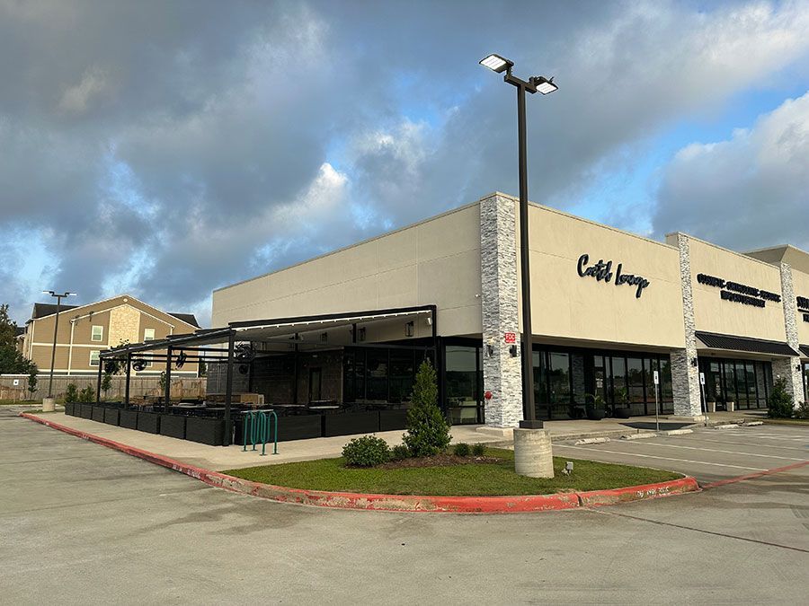 A large white building with a lot of windows and a parking lot in front of it.