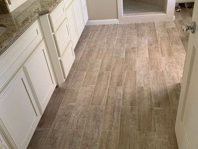 A bathroom with a wooden floor and white cabinets.