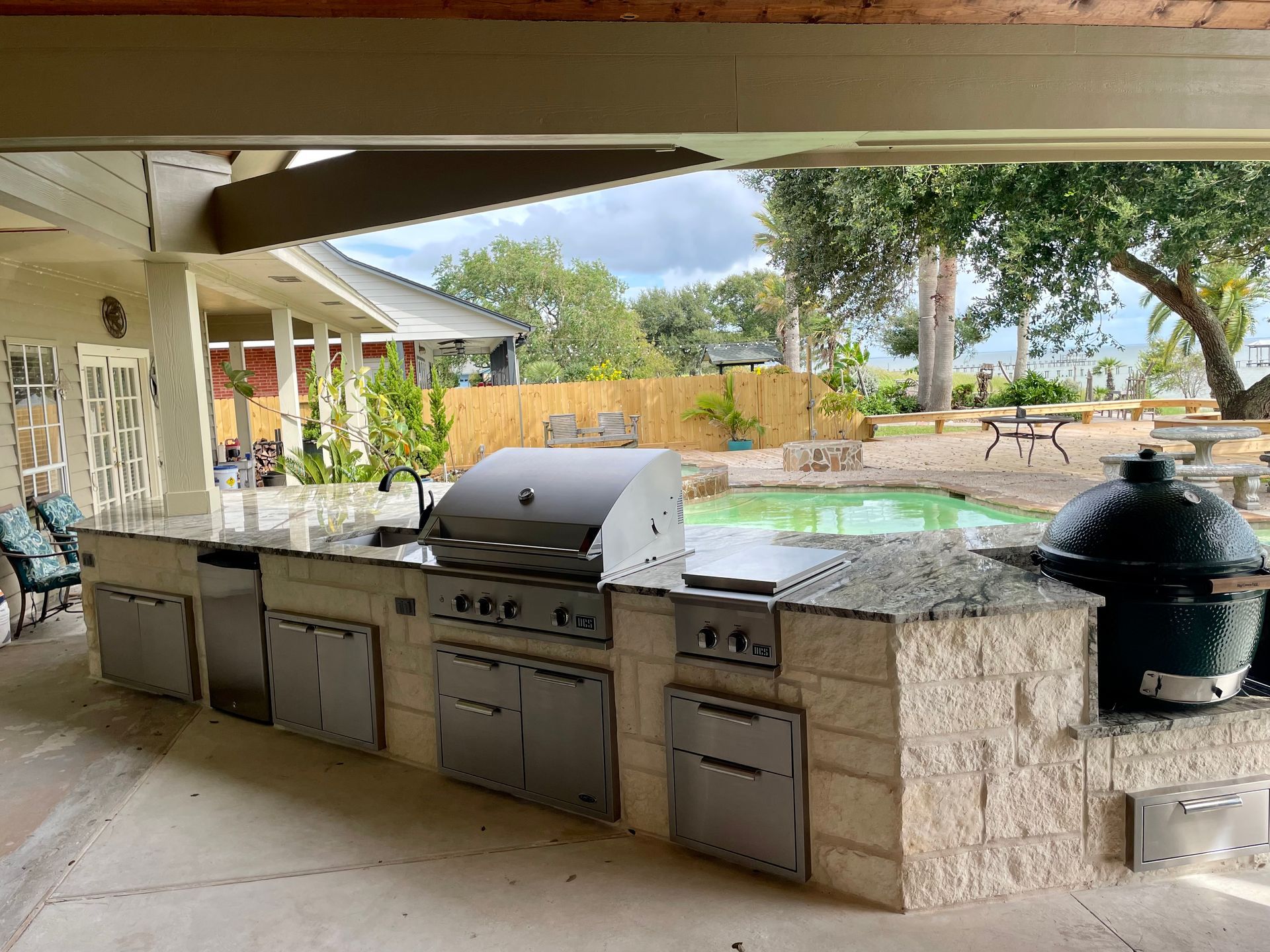 A large outdoor kitchen with a grill and a large green egg.