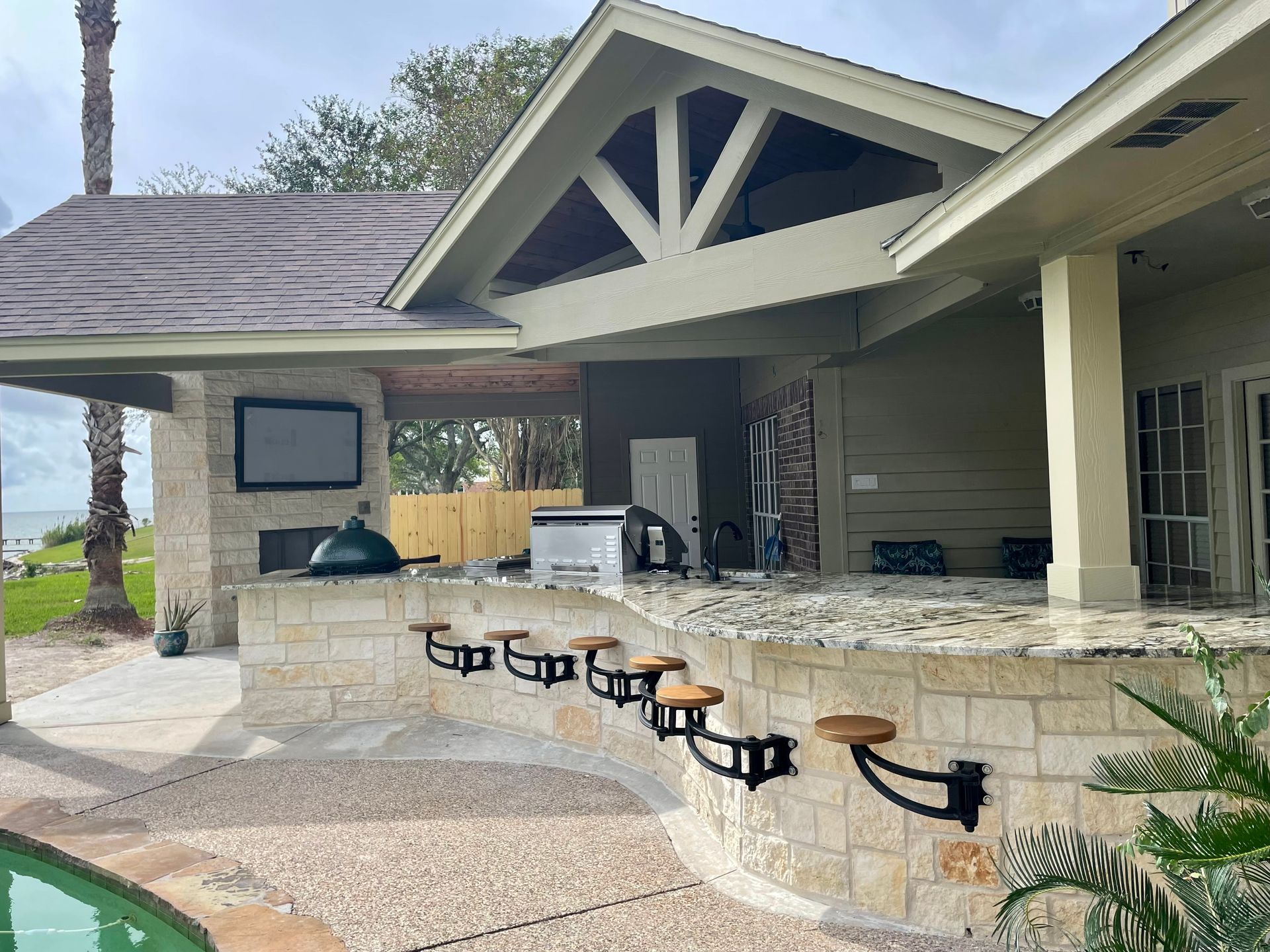 A house with a patio area and a swimming pool in front of it.
