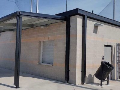 A brick building with a canopy over it and a trash can in front of it.