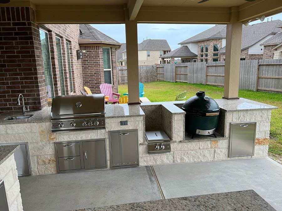 An outdoor kitchen with a grill , sink , and large green egg.