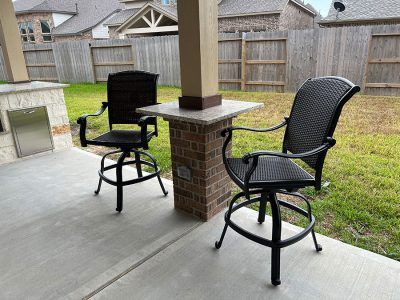 Two chairs are sitting on a patio next to a table.