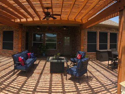 A patio with furniture and a ceiling fan under a pergola.