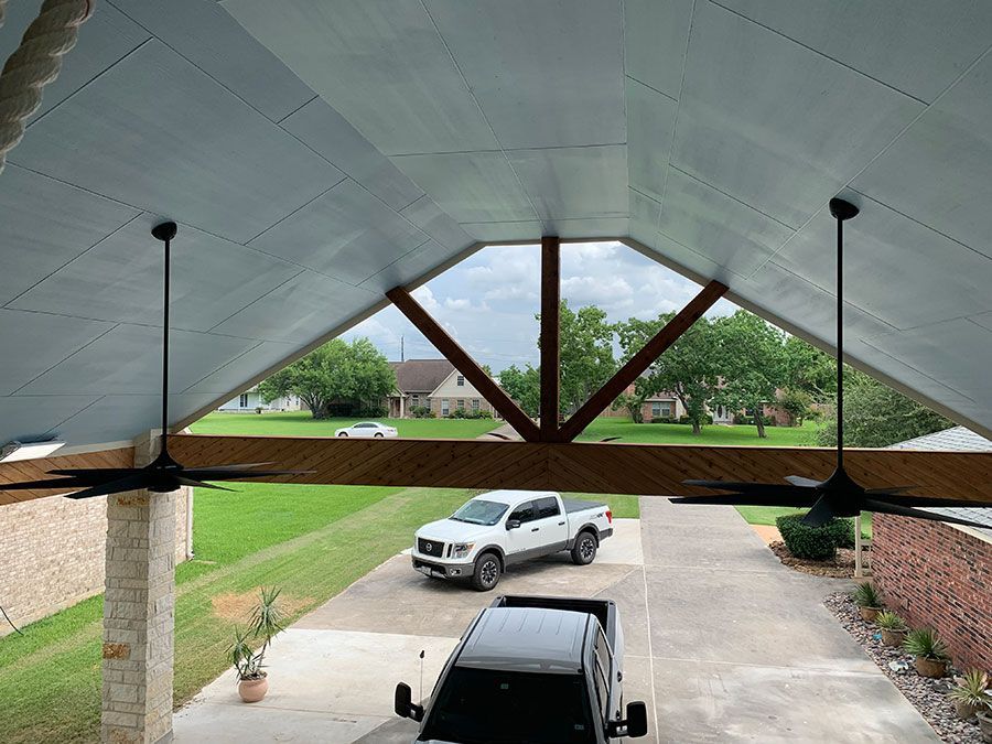 A truck is parked in a driveway under a ceiling fan.