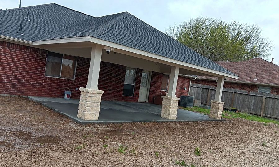 A brick house with a covered patio in front of it.