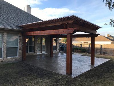 A wooden pergola is sitting in the backyard of a house.