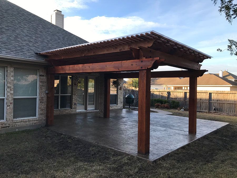 A wooden pergola is sitting in the backyard of a house.
