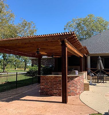 A patio with a wooden pergola and a brick counter top.
