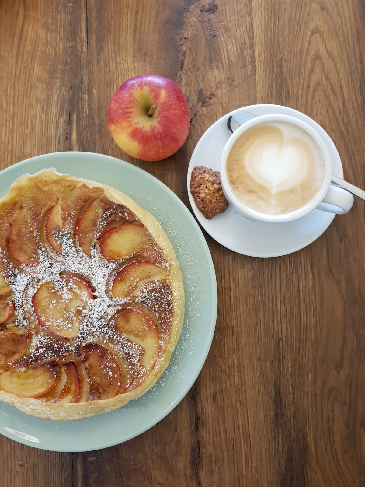 Desservariation und Heißgetränk. Dazwischen steht ein Apfel