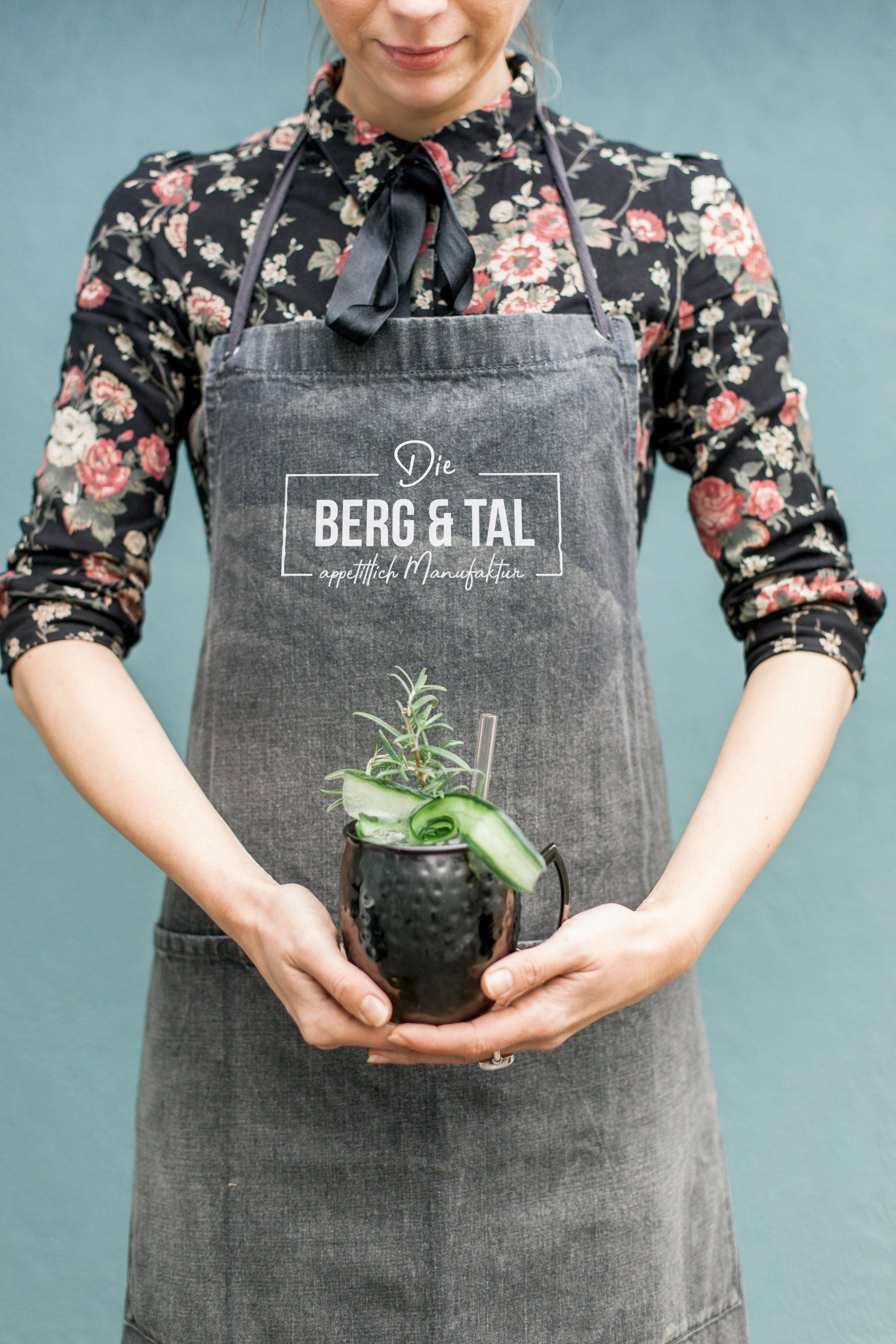 Logo Berg un Tal auf einer Schürze, die Tatjana trägt. Der Bildausschnitt ist ab Kinn bis Bauchnabel.