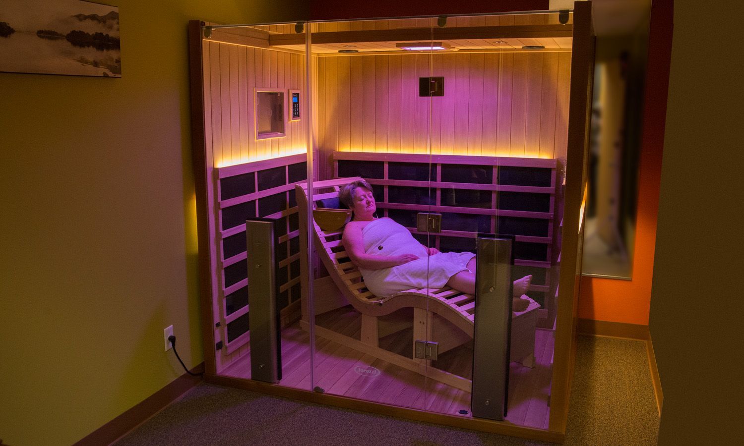 A woman is laying in a chair in an infrared sauna.