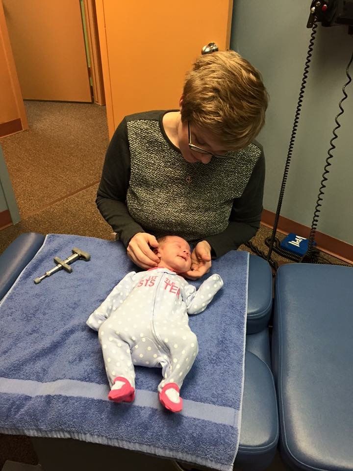 A woman is examining a baby on a table.