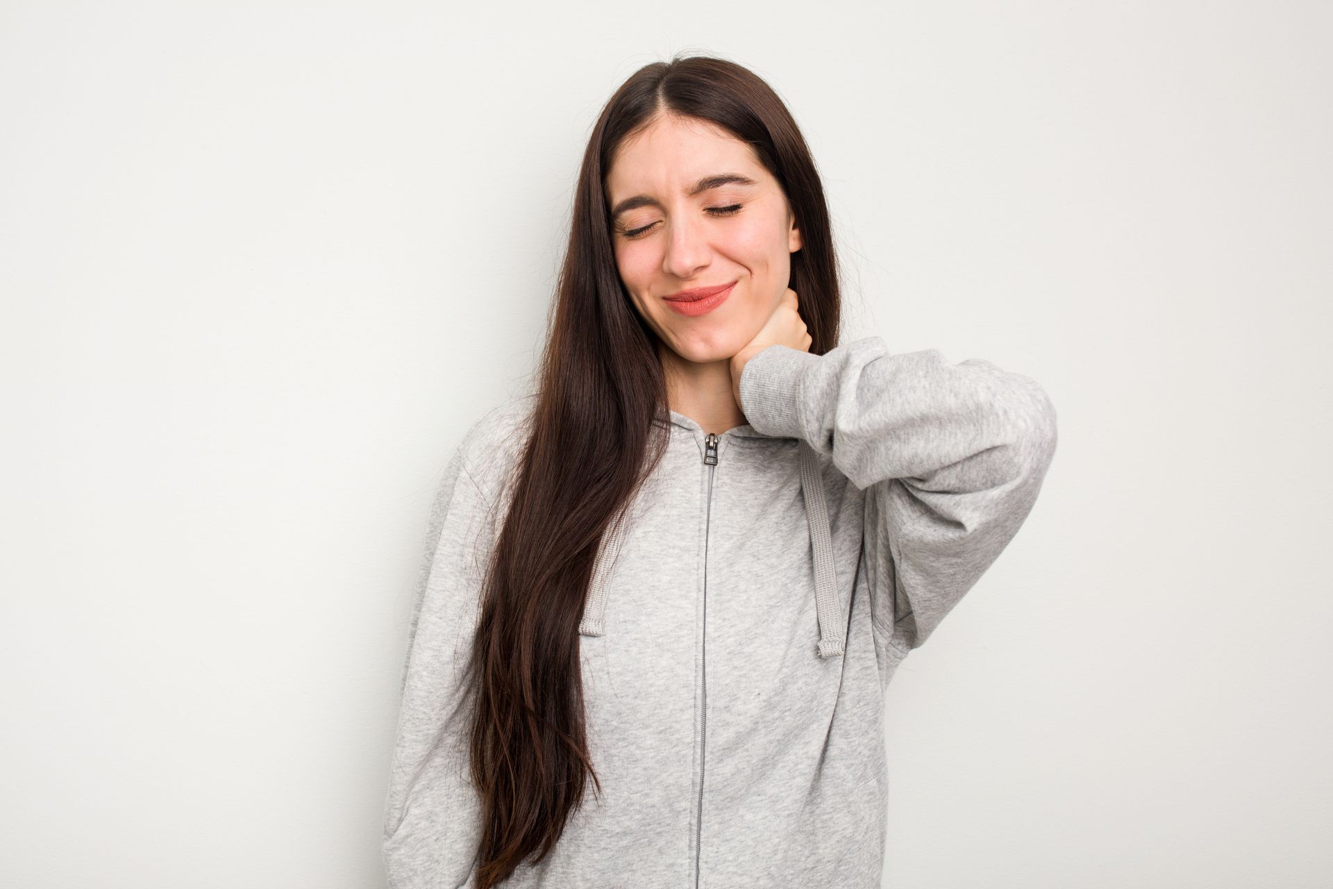 A young woman is holding her neck because she has a sore neck.