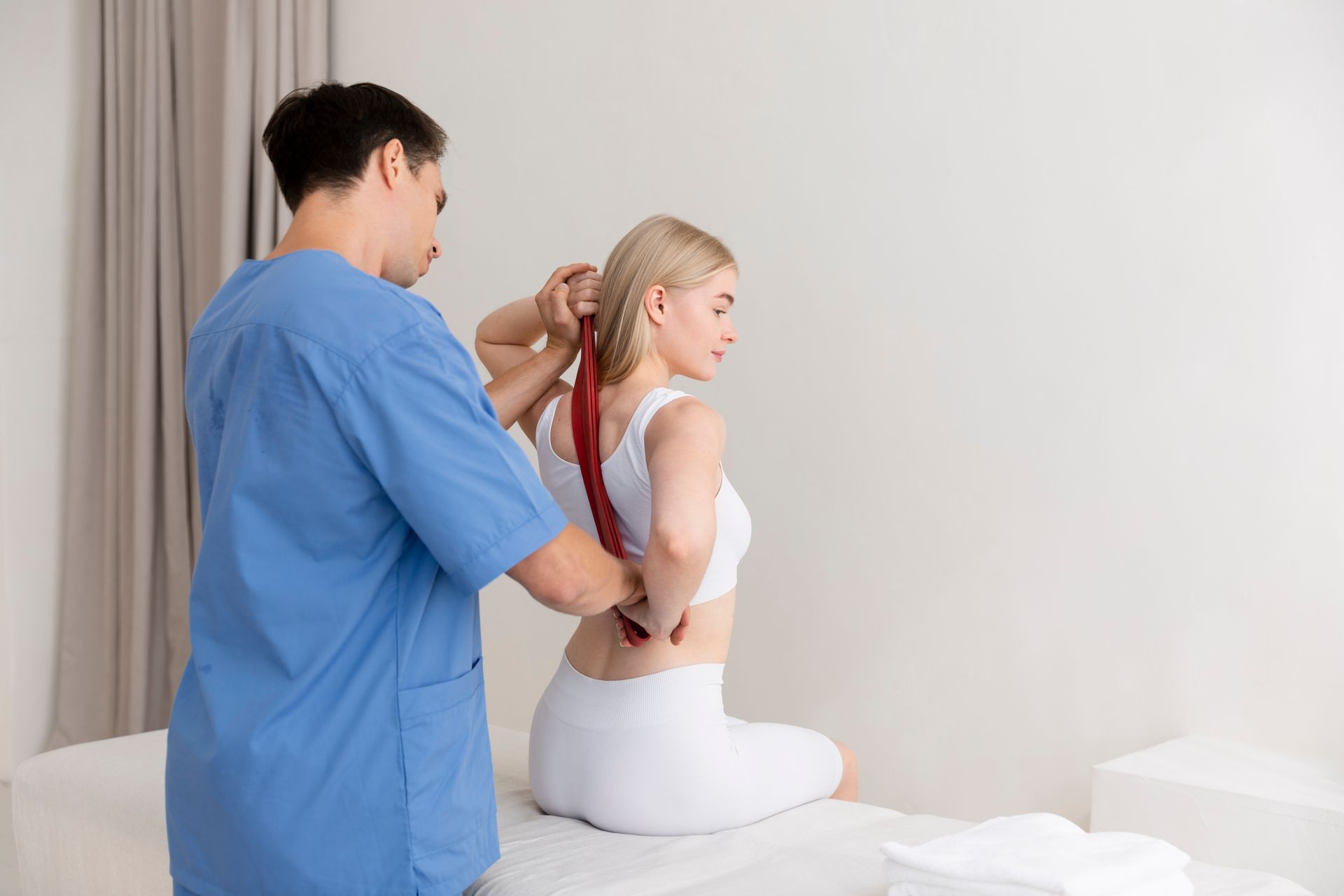 A woman is sitting on a bed getting a massage from a doctor.