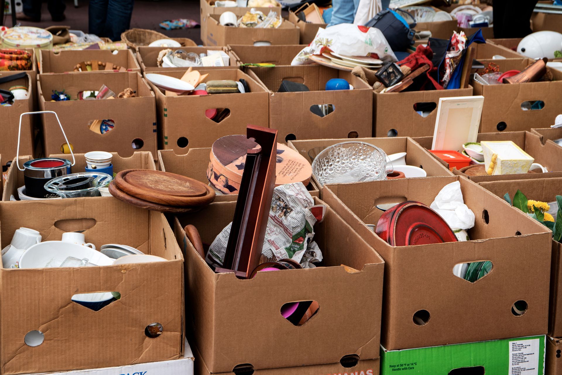Cardboard boxes overflowing with items at a flea market, outdoors. Cardboard boxes overflowing with items at a flea market, outdoors.