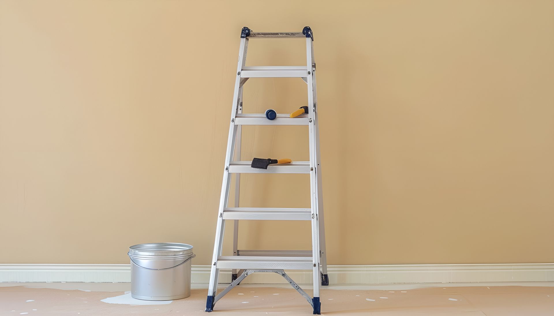 Ladder leaning against a beige wall, with a paint can and paint supplies, in a room.