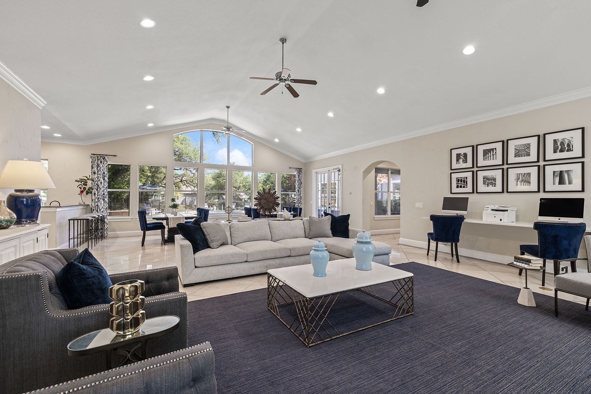 Spacious living room with vaulted ceiling, large windows, and blue and white decor; features include a sectional sofa and a large blue rug at Marquis at TPC, offers pet-friendly apartments on Evans road.