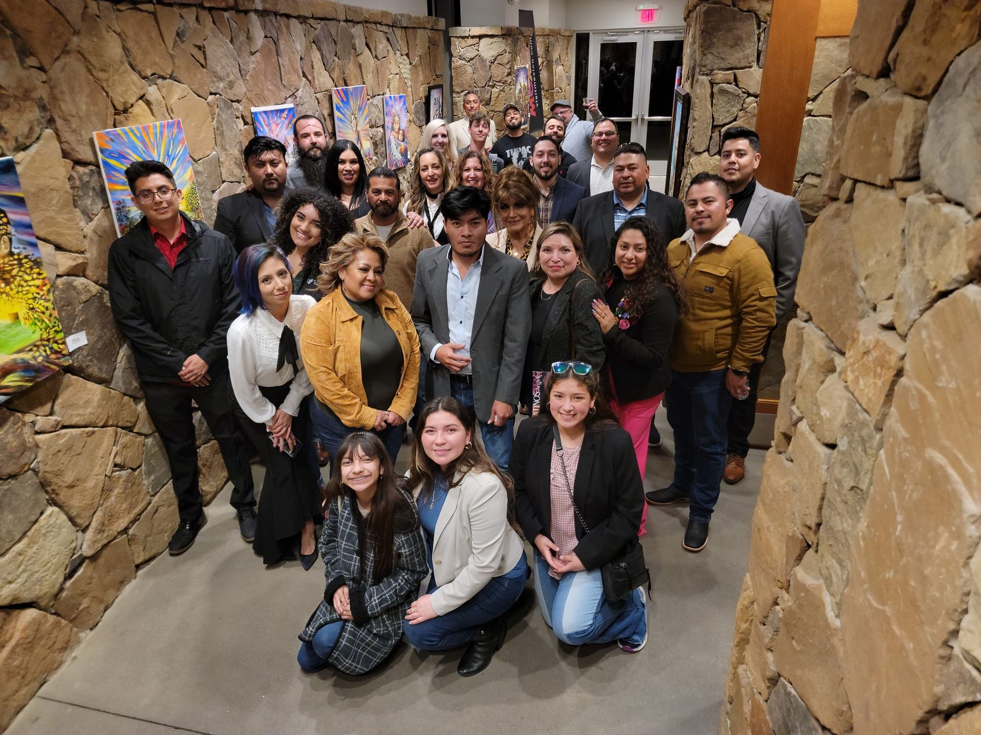 A group of people are posing for a picture in front of a stone wall.