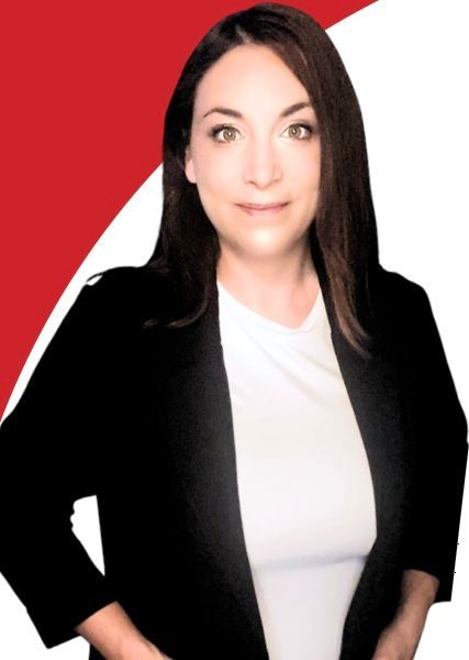 A woman is sitting at a desk with a laptop and a vase of flowers.