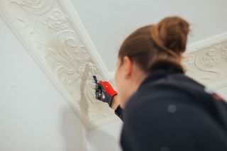 A woman is painting a ceiling with a brush. A woman is painting a ceiling with a brush.