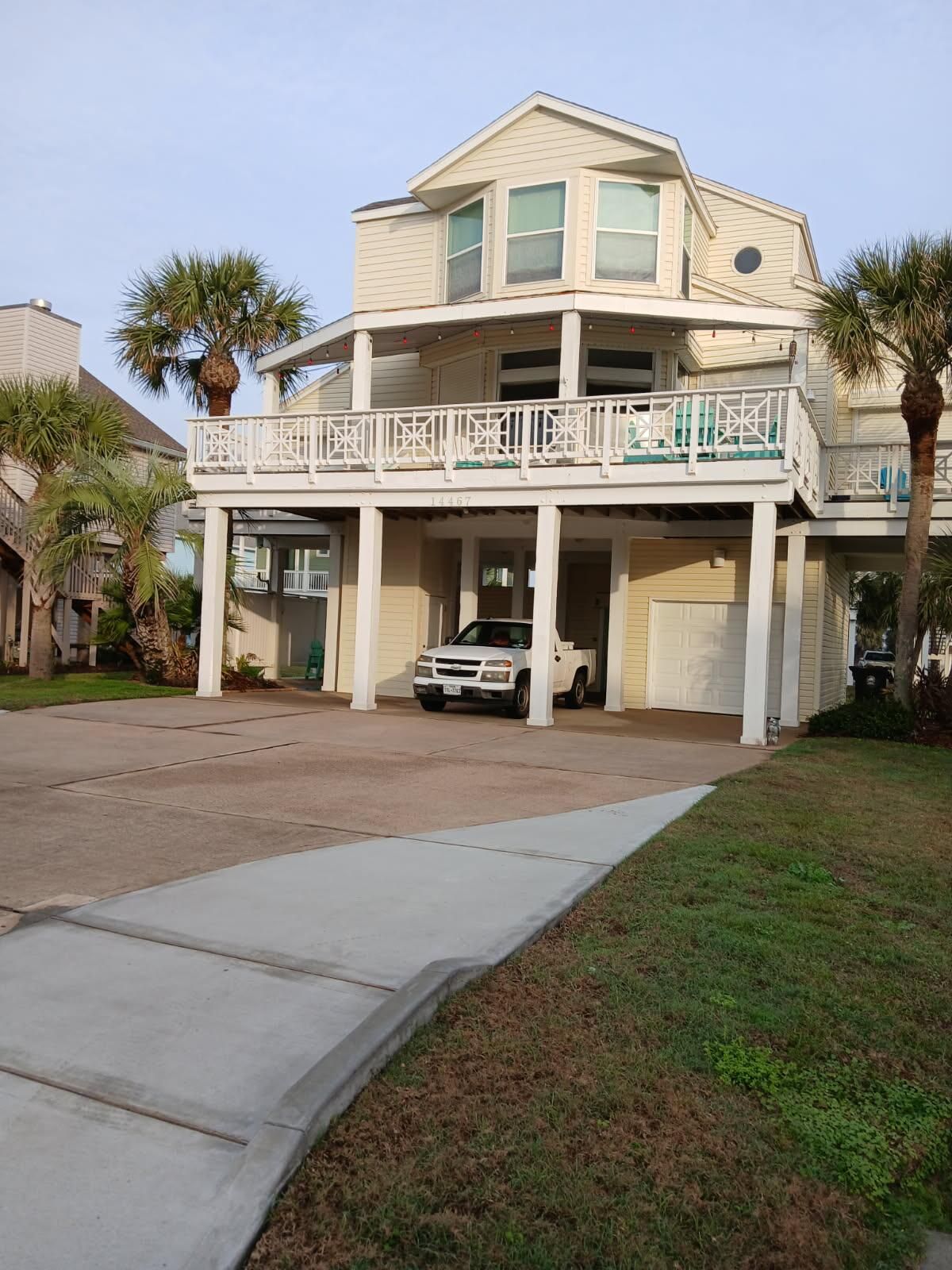 A white truck is parked in front of a large house