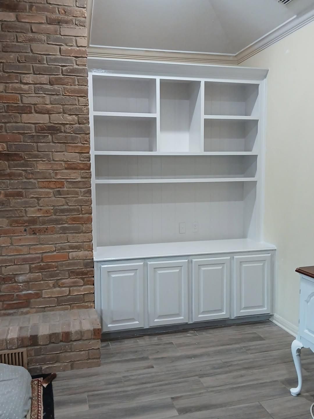 A living room with white cabinets and a brick wall.
