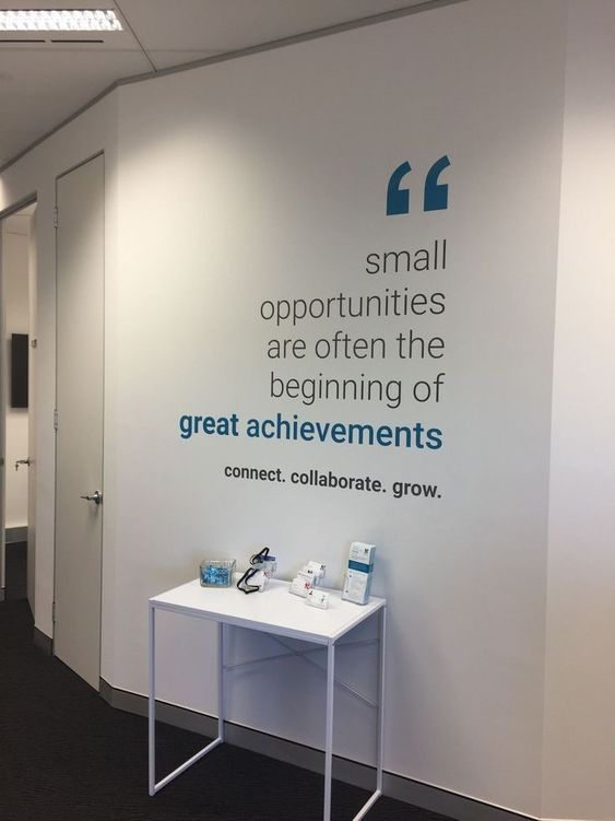 Hallway wall with quote decal above a small white table displaying brochures and water glasses