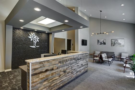 Modern office lobby with reception desk, gray carpet, wall art, and seating area